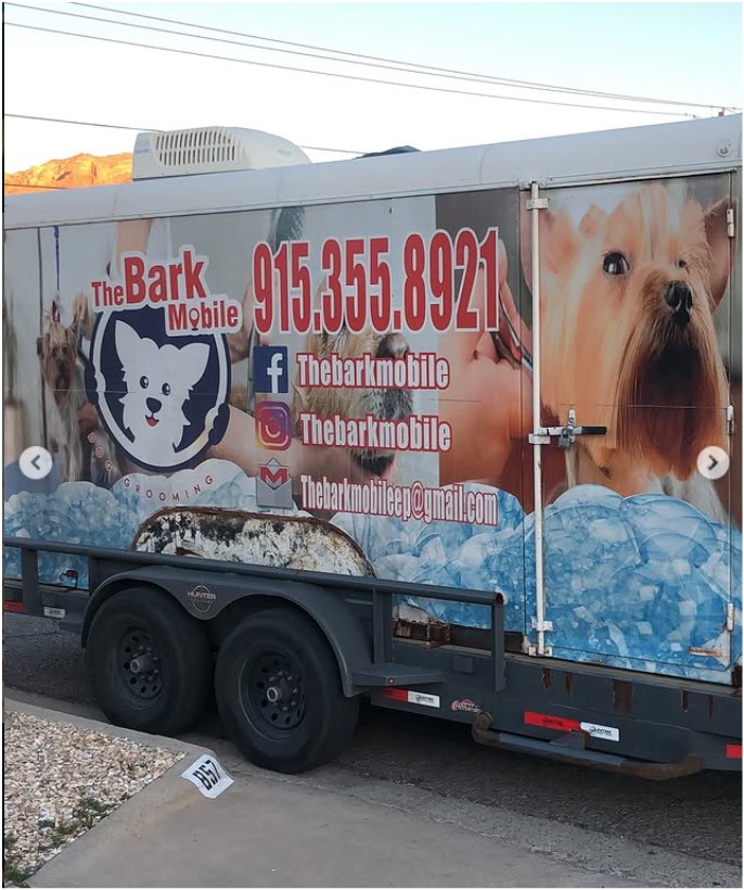 The Bark Mobile grooming trailer wrapped with dog photos and contact details