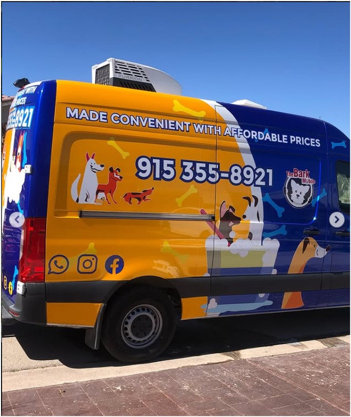 Side of a yellow and blue Bark Mobile grooming van reading Made Convenient With Affordable Prices